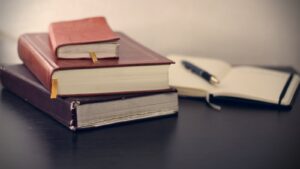 photographie sélective de trois livres à côté d'un cahier ouvert
