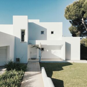maison en béton blanc près d'un arbre vert pendant la journée