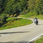 Route de montagne sinueuse avec une moto et des voitures en circulation
