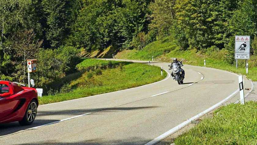 Route de montagne sinueuse avec une moto et des voitures en circulation