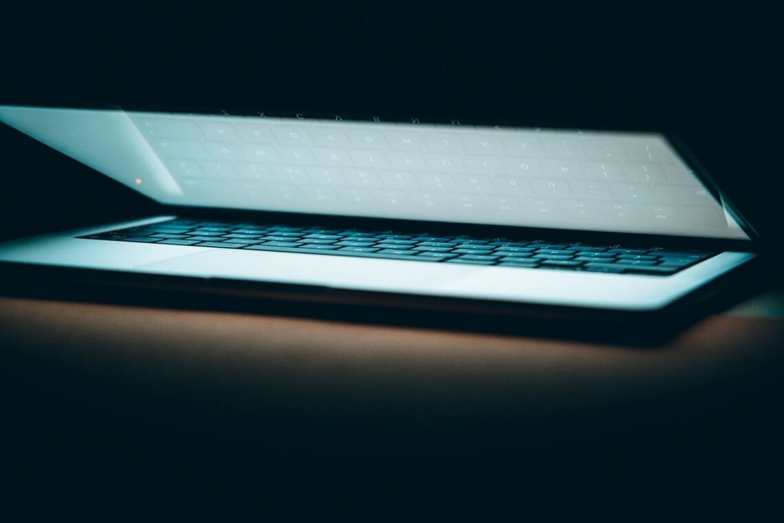 Ordinateur portable ouvert dans l'obscurité, clavier rétroéclairé, écran luminescent