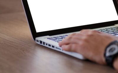 Personne utilisant un ordinateur portable avec écran blanc sur bureau en bois, vue de côté