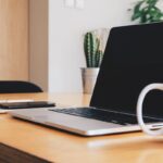Espace de travail avec ordinateur portable, téléphone, carnet et tasse sur bureau en bois