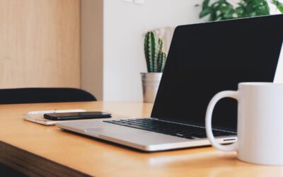 Espace de travail avec ordinateur portable, téléphone, carnet et tasse sur bureau en bois