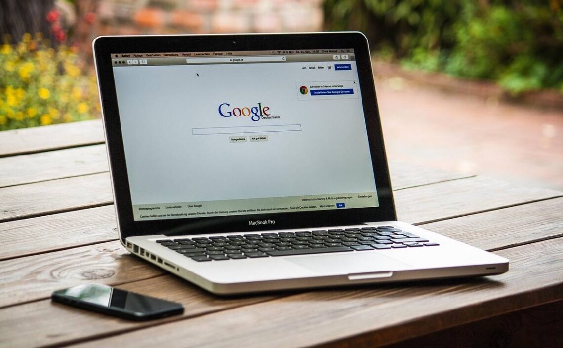 Un ordinateur portable affiche Google sur une table en bois à l'extérieur