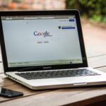 Un ordinateur portable affiche Google sur une table en bois à l'extérieur