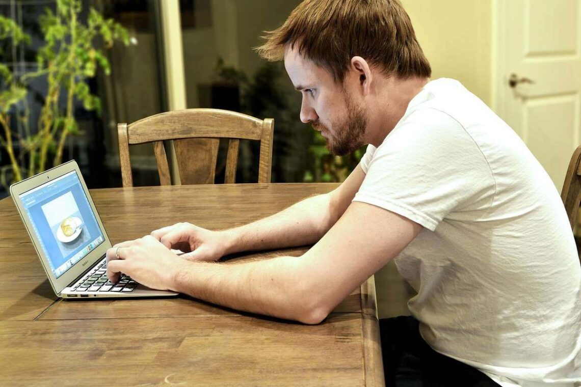 Homme travaillant sur un ordinateur portable à un bureau en bois