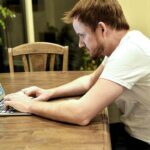Homme travaillant sur un ordinateur portable à un bureau en bois