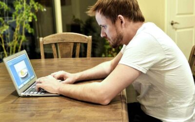 Homme travaillant sur un ordinateur portable à un bureau en bois