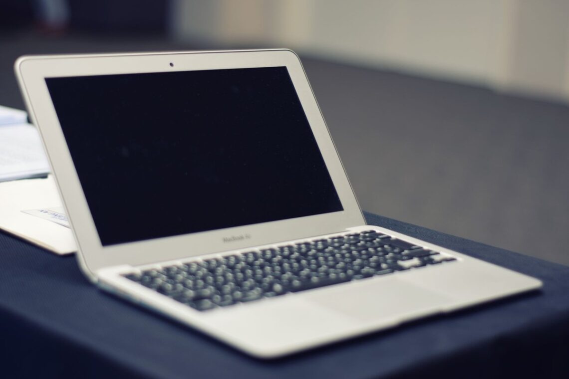 Ordinateur portable blanc avec écran noir posé sur une surface de travail grise