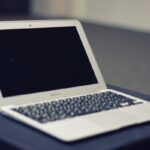 Ordinateur portable blanc avec écran noir posé sur une surface de travail grise