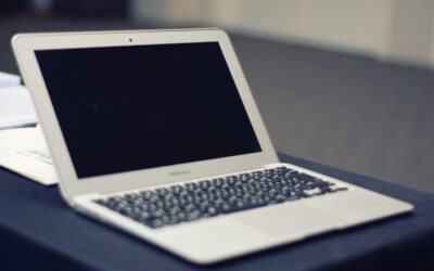 Ordinateur portable blanc avec écran noir posé sur une surface de travail grise