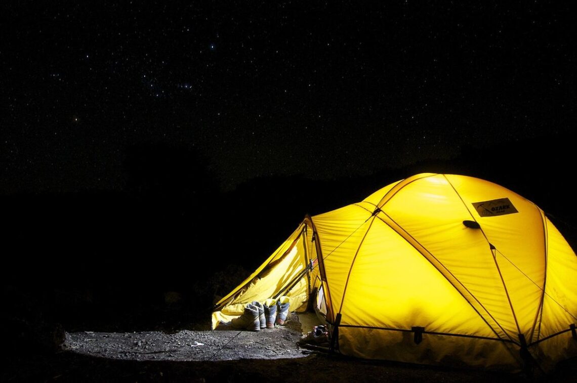 Tente jaune lumineuse dans le noir ciel étoilé