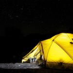 Tente jaune lumineuse dans le noir ciel étoilé