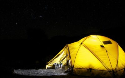 Tente jaune lumineuse dans le noir ciel étoilé
