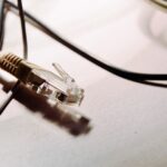 Un connecteur RJ45 et plusieurs câbles noirs sur une surface claire