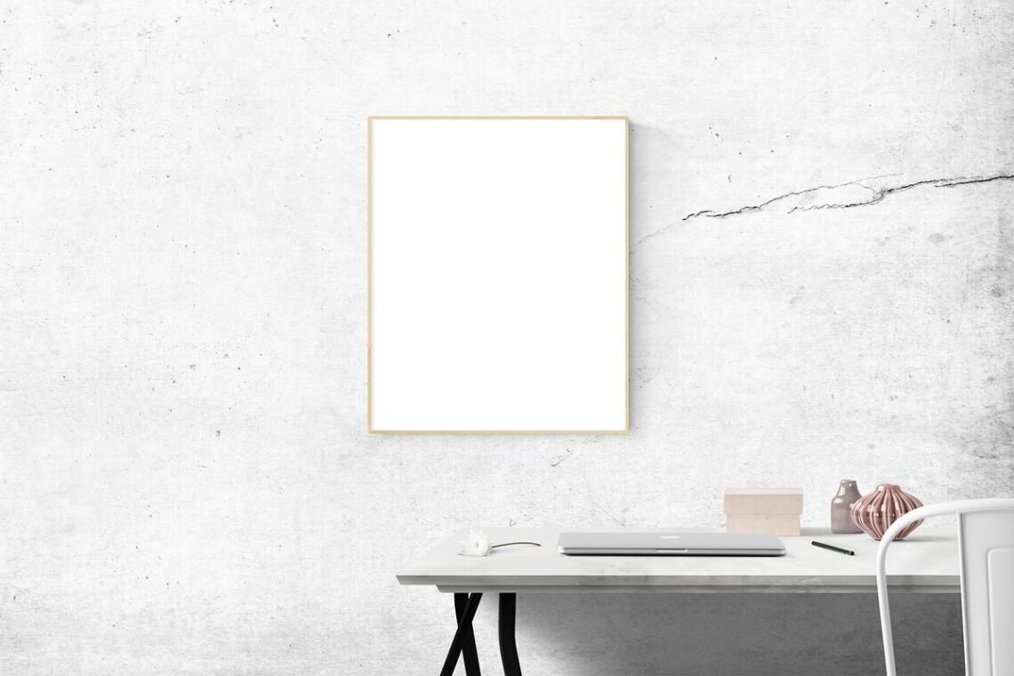 Bureau avec ordinateur et objets, tableau vide, mur texturé