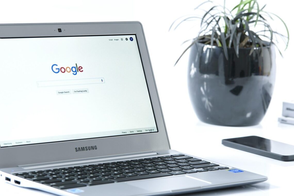 Laptop Samsung avec Google sur l'écran, smartphone et plante en pot noir à proximité