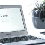 Laptop Samsung avec Google sur l'écran, smartphone et plante en pot noir à proximité