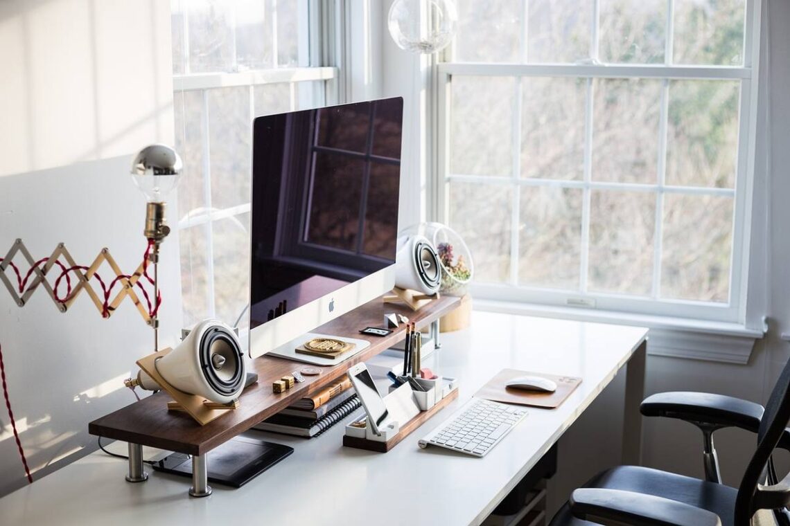 Un espace de travail moderne avec ordinateur, haut-parleurs et lumière naturelle